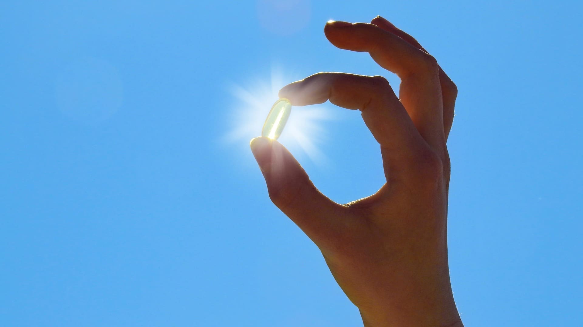 Women’s Health SA-Vitamin D Deficiency South Africa Hand holding vitamin D supplement in front of sun in blue sky