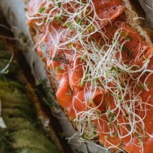 Two slices of toast– one with avocado and the other with salmon
