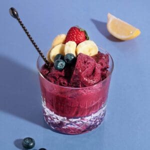 Blueberry and banana smoothie in glass on purple background