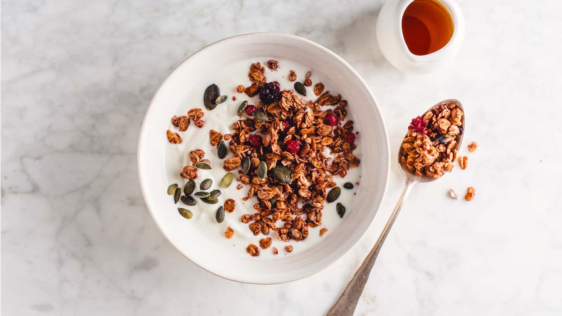 Bowl of granola and fresh fruit on a plain grey background