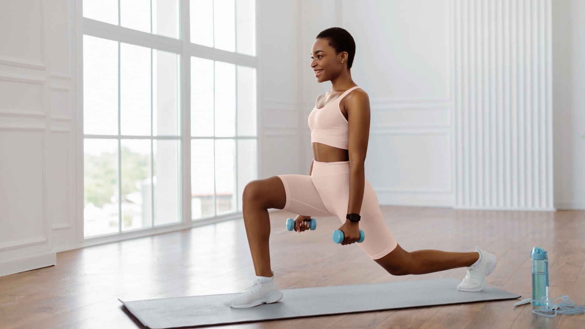 Woman in pink workout clothes doing lunge for at-home quick HIIT workout