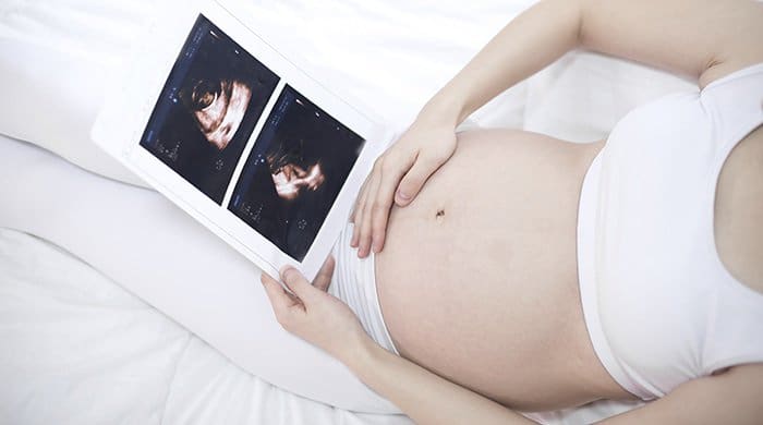 Woman holding her pregnant tummy looking at her ultrasound and thinking about having a c-section