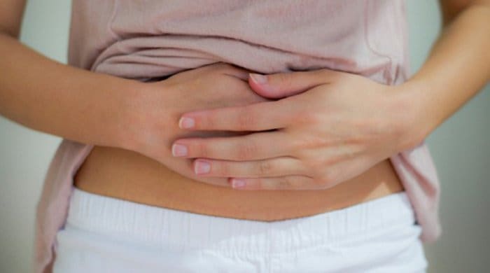 A woman with stomach cramps because she has food poisoning or a stomach bug