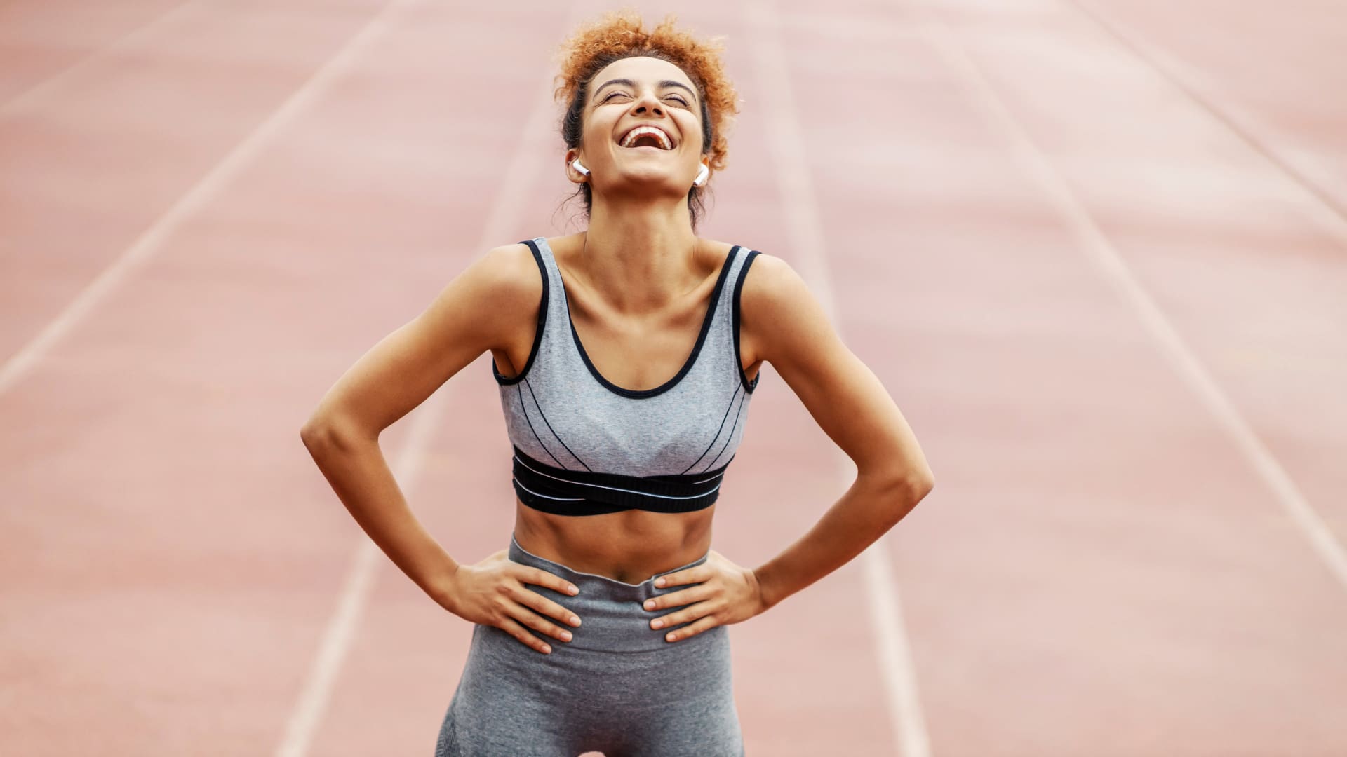 woman laughing on athletic track with exercise clothing