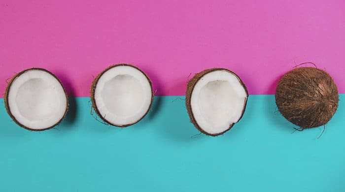 Coconuts and coconut oil on a pink and blue background
