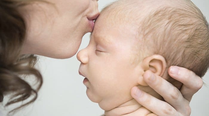 baby a close-up of a woman kissing a baby