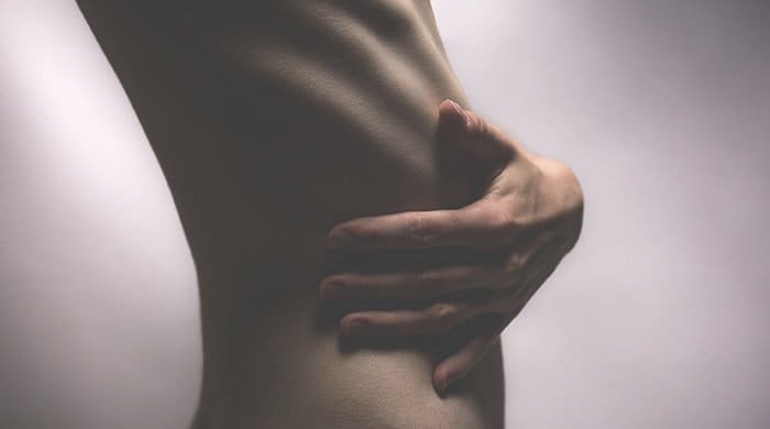 A woman holding her ribs because she has an eating disorder