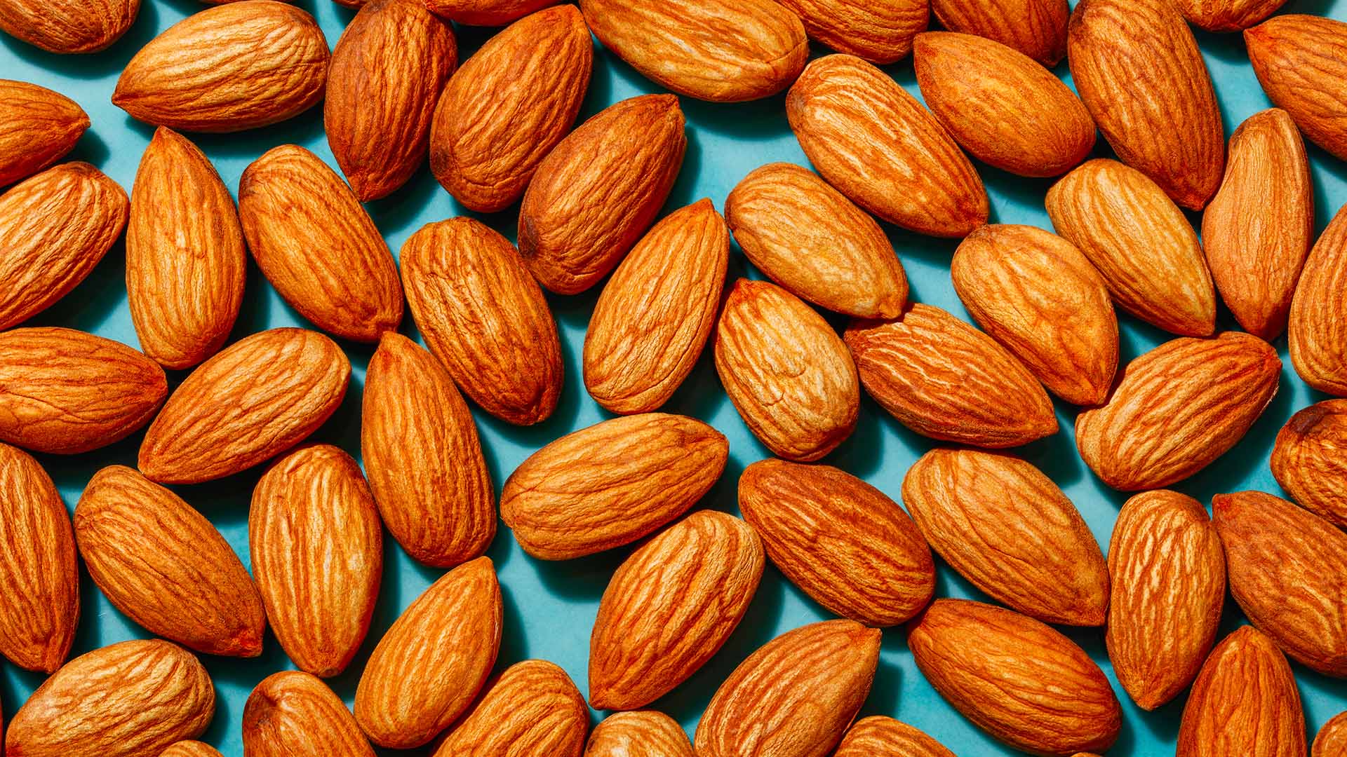 Almonds placed on a turquoise backdrop
