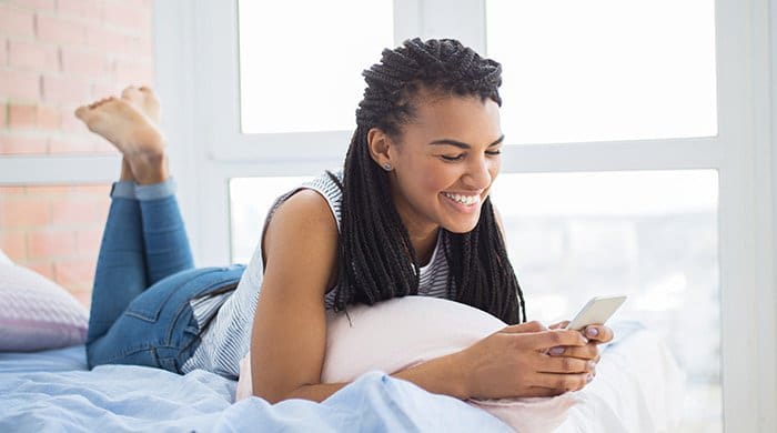 A woman lying on a bed smiling because she has no fear of rejection