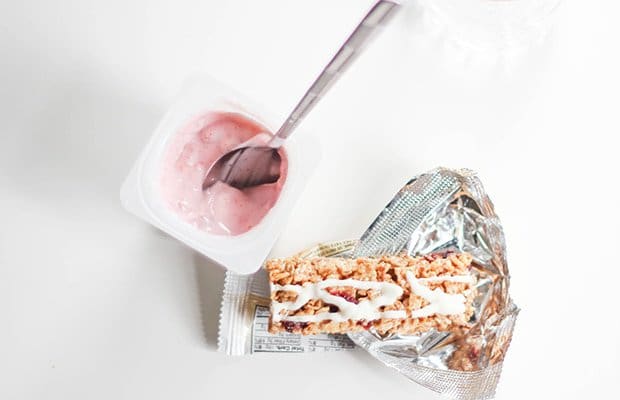 A tub of strawberry yoghurt and a snack bar on a desk