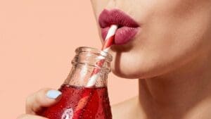 Close-up of woman who might have diabetes symptoms in women drinking red drink from straw