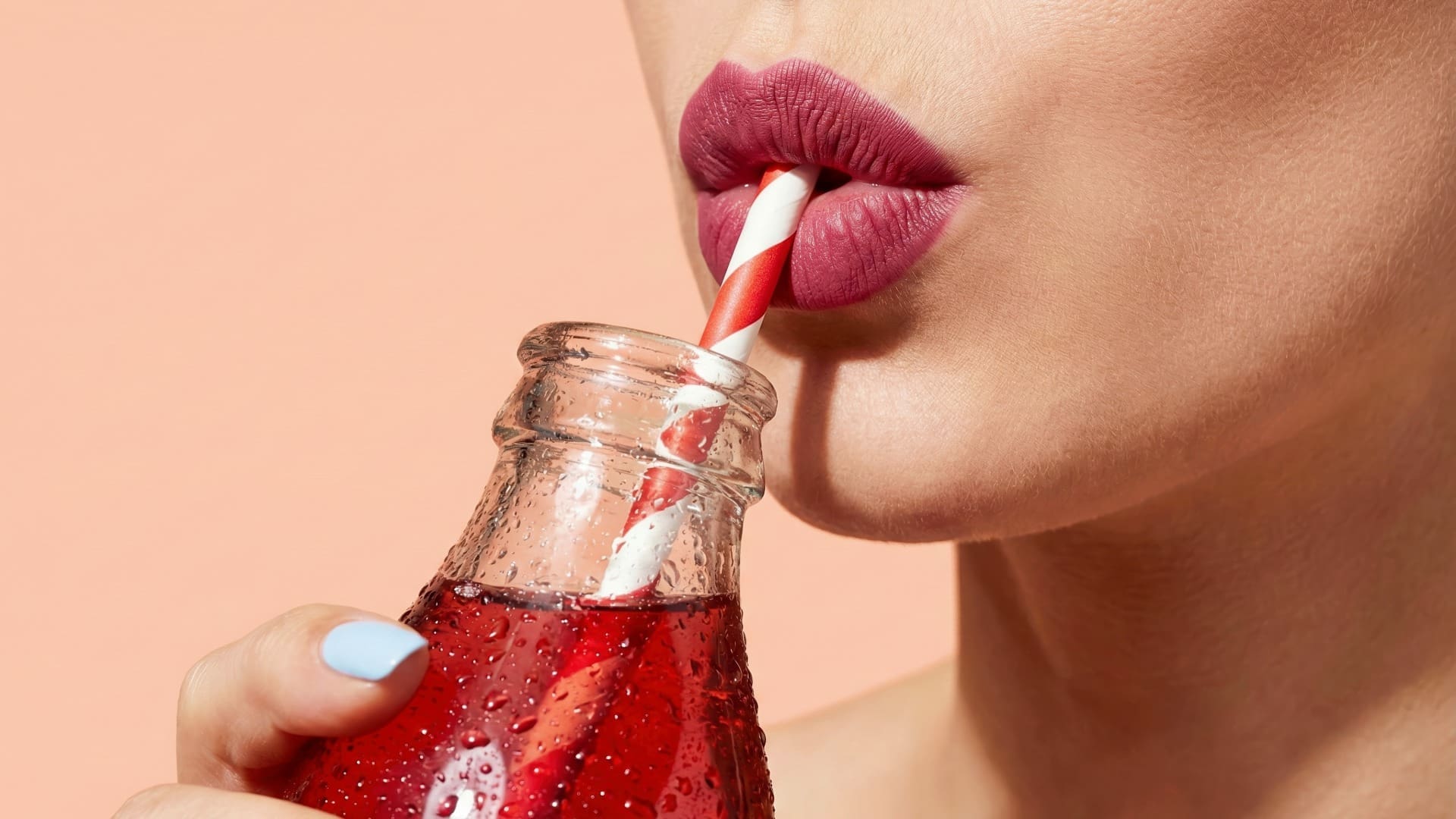 Close-up of woman who might have diabetes symptoms in women drinking red drink from straw