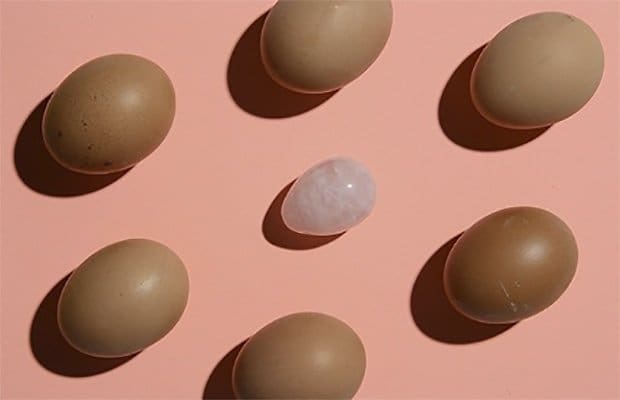 jade egg with hens eggs on a peach background