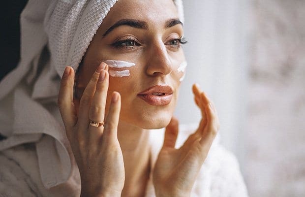 a woman with milia applying face cream