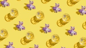 binge-drinking flatlay of drinks on yellow surface and purple flowers