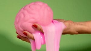 if you have year-end burnout, your brain feels like this image of a hand holding a pink brain, melting goo over the hand