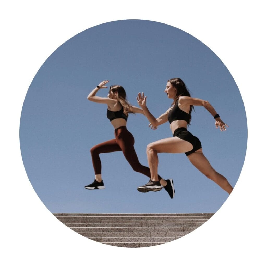 Two women running against blue backdrop 