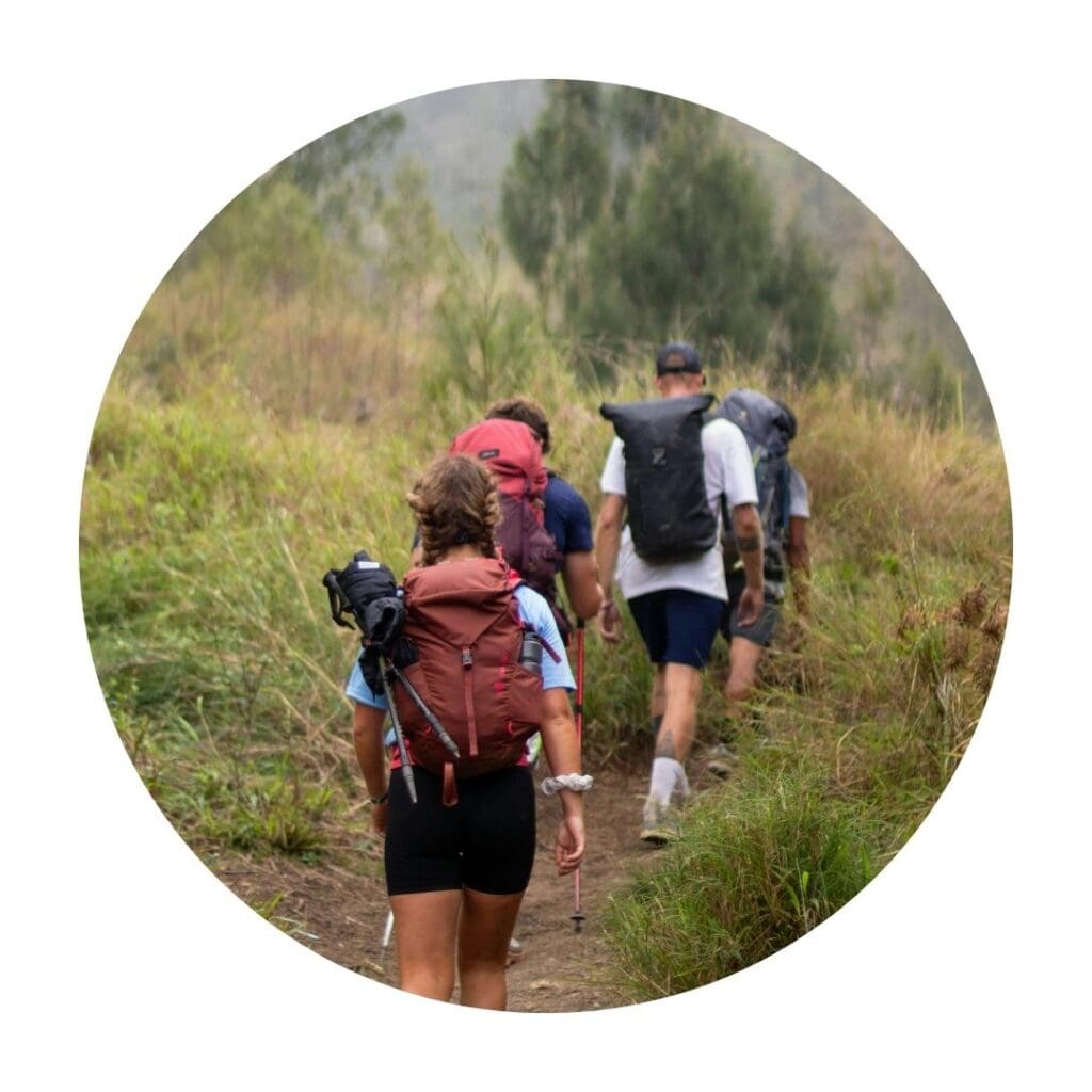 People with backpacks hiking through green trail
