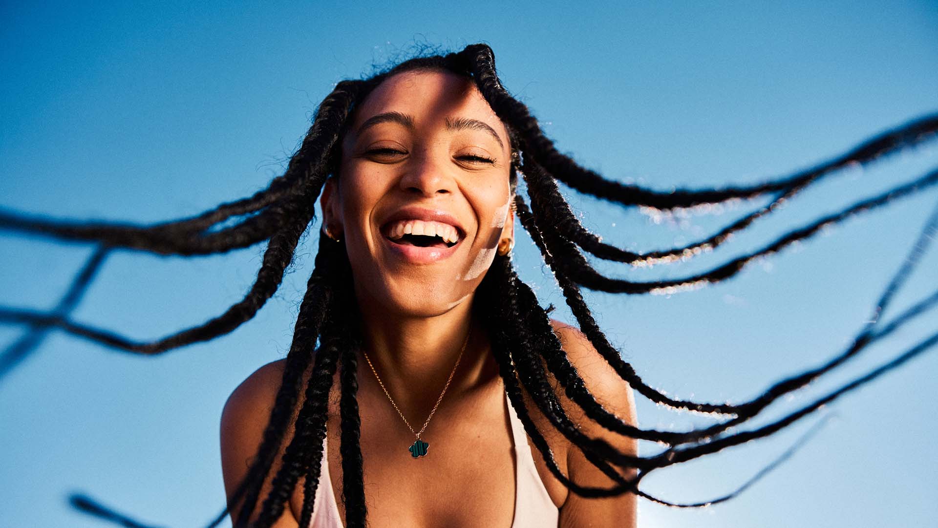 Portrait of attractive young woman tossing her long braided hair and being happy