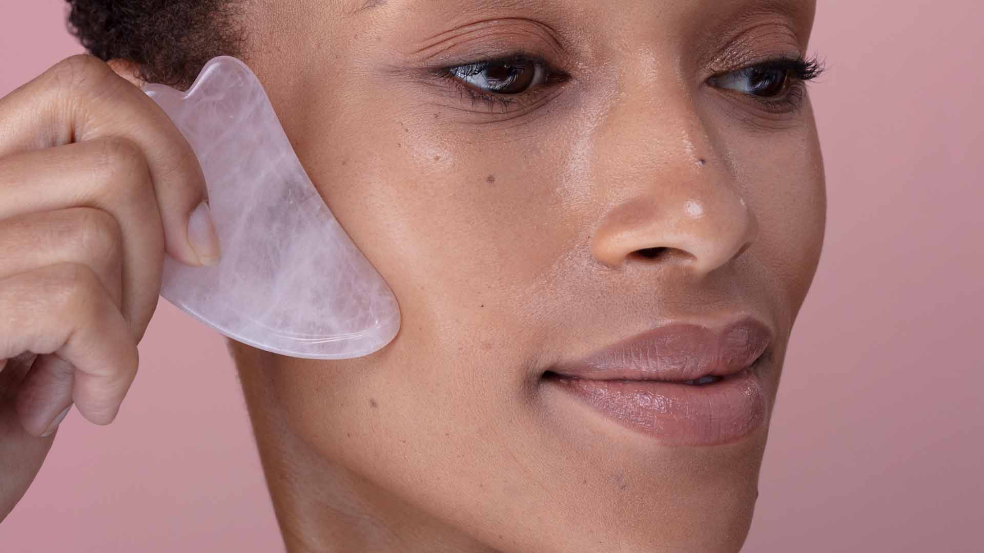 Close-up of woman massaging face with rose quartz gua sha