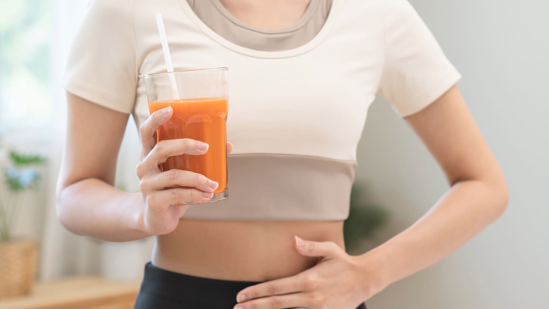 Woman with crop top and orange juice doing juice cleanse