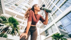 Woman drinking water or recovery shake after her run outdoors