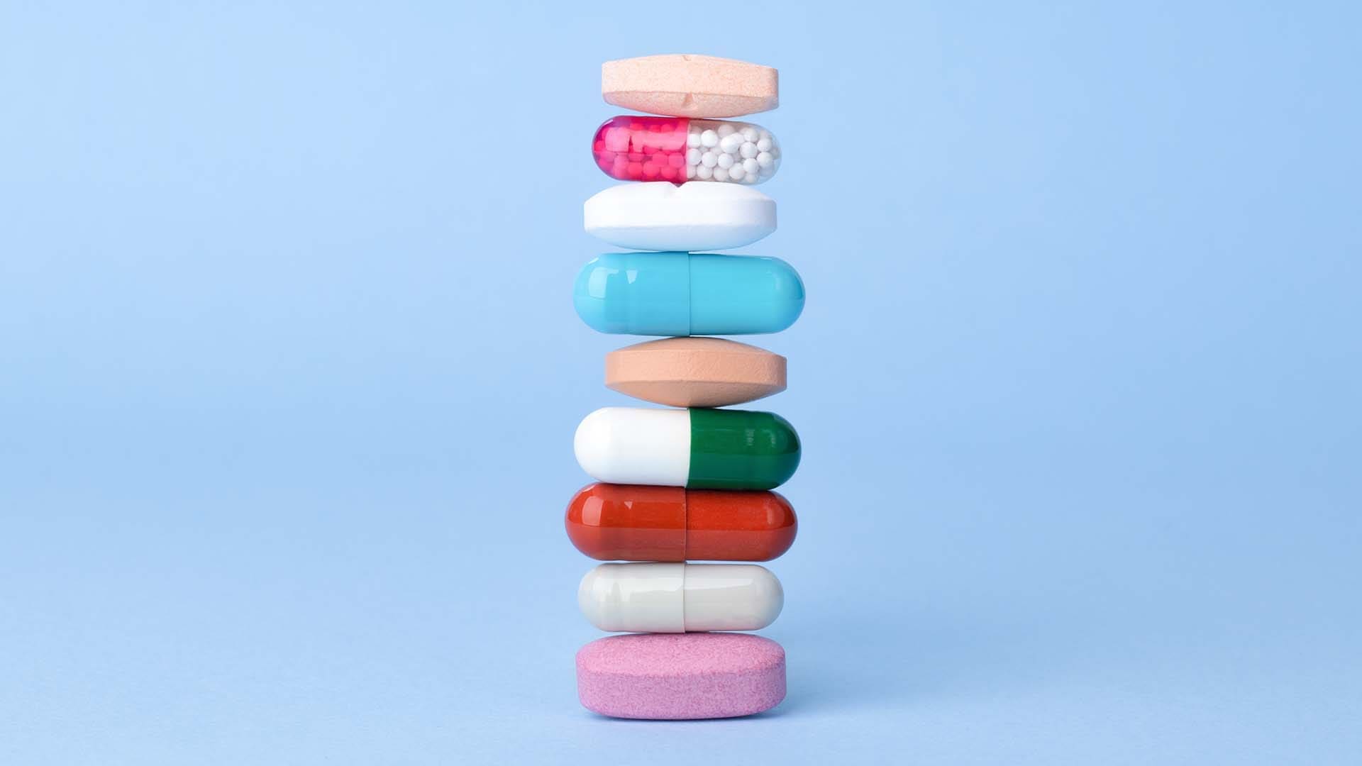 Peptide Stacking Explained Assorted pills, vitamins and supplements balancing on each other